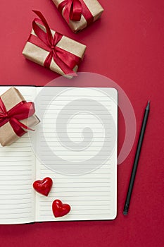 Valentine's Day mock up. Open notebook with red hearts and gift boxes, on red background, copy space for text