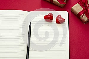 Valentine's Day mock up. Open notebook with red hearts and gift boxes, on red background, copy space for text