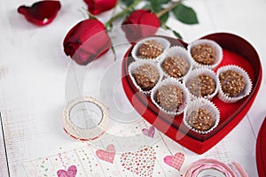 Valentine`s day. Nutty chocolate in a red heart box and red roses for Valentine`s or anniversary present. Soft focus on the nutt