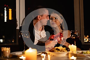 Valentine's day passionate couple having dinner by candlelight, night meeting man woman giving a gift, romantic date