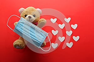 Valentine`s Day in pendemic for covid-19, teddy bear, box of chocolates, flowers and hearts with protection mask clinical use photo