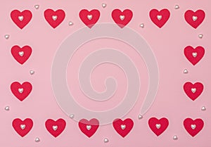 Valentine`s Day pink background with red and pearl hearts. Valentine greeting card. Flat lay style