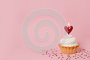 Valentine`s day pink background. Vanilla cupcake decorated red heart candle