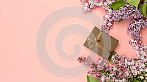 Valentine`s day presents. Gift box and lilac flowers on romantic pink background. 16x9 banner, copy space.