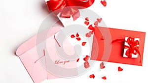 Valentine`s Day. Red and open pink envelopes with small cut paper heart and gift box with red bow. Writing a love letter. Message