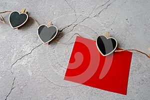 On Valentine's Day, a red sheet of paper hangs on a string of pins with black hearts on a gray background to