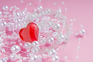 Valentine`s day romantic card red heart with white beads on a pink background