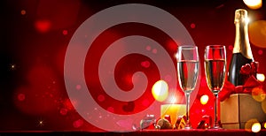 Valentine`s Day romantic dinner. Champagne, candles and gift box over red background