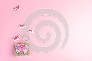 Valentine`s day sale concept. Decorative wicker handbag and hearts with discount percentages on pink backdrop