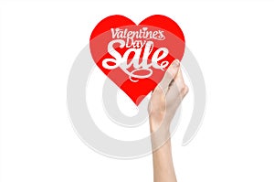 Valentine's Day and sale topic: Hand holding a card in the form of a red heart with the word Sale isolated on white background