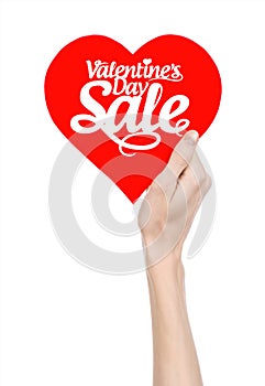 Valentine's Day and sale topic: Hand holding a card in the form of a red heart with the word Sale isolated on white background