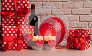 Valentine`s day still life with a bottle of wine, gifts, balloons and heart shaped candles