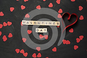 Valentine's Day text word wooden blocks with paper hearts on black cement floor. Valentine's Day 14 February holiday