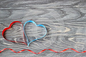 Valentine`s Day . Two hearts of ribbons of red and blue on a bac