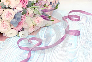 Valentine`s Day. Valentine Gift. Satin ribbon in Heart shape and bouquet of flowers on blue wooden background.