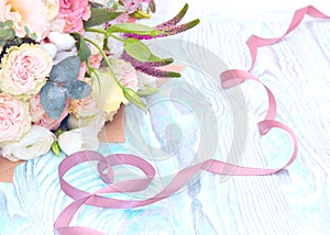 Valentine`s Day. Valentine Gift. Satin ribbon in Heart shape and bouquet of flowers on blue wooden background.