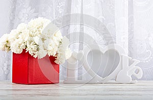 Bouquet of white roses in a red box and a white photo frame close-up.