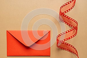 Valentine\'s day or Wedding romantic concept. Twisted decorative ribbon and red envelope with red hearts on beige background