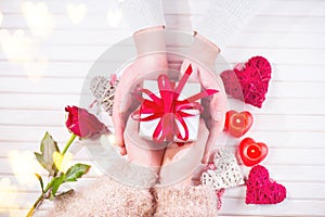 Valentine`s Day. Young couple hands holding gift box over white wooden background. Love concept