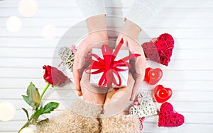 Valentine`s Day. Young couple hands holding gift box over white wooden background. Love concept