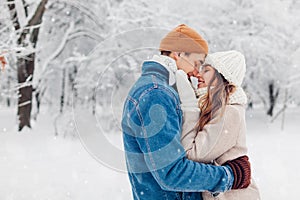 Valentine& x27;s day. Young loving couple walking in winter park. Man and woman hugging enjoying snowy landscape outdoors