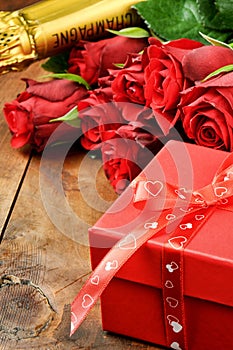 Valentine's setting with red roses, champagne and gift box