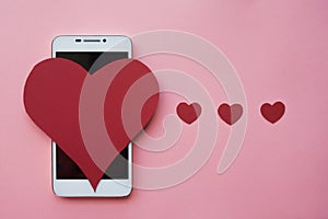 Valentine and smartphone. The concept to like in social networks or Dating app. pink background