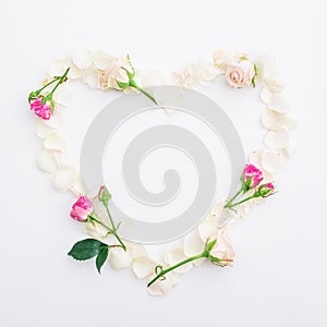 Valentines background. Heart symbol of roses petals on white background. Flat lay, Top view.