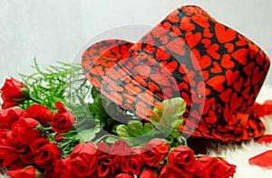 Valentines black hat, with red hearts, on top of dozen small red roses,