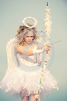 Valentines day. Angel child girl with curly blonde hair. Charming curly little girl in white dress and wings - angel