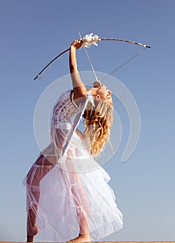 Valentines day. Angel cupid with bow and arrow. Woman in white dress. Portrait of sweet angelic girl.