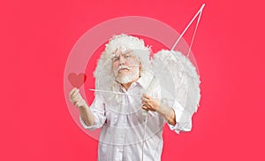 Valentines Day. Angel in white wings with bow and arrow hold red paper heart. Valentine cupid. Love.