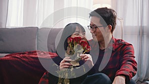 Valentines day or anniversary concept. Young woman smelling red roses while her boyfriend is kissing and hugging her