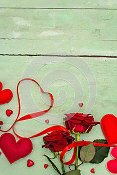 Valentines Day background with assorted hearts, fresh burgundy roses and red festive ribbon