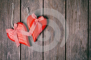 Valentines day background. Couple of red hearts with checkered ribbon on wooden background. Top view