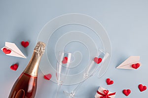 Valentines Day background. Gift box , alarm clock , red candy  hearts and paper plane, two champagne glasses on blue background