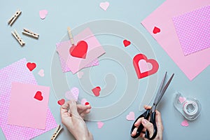 Valentines day background. Hands making Valentine card with heart and on the blue background