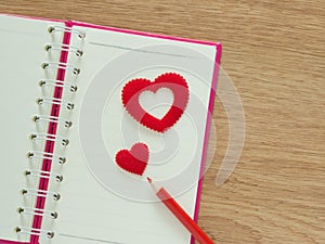 Valentines day background with red hearts, book for diary and color pencils on wood floor. Love and Valentine concept