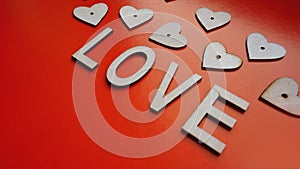 Valentines Day background with red hearts and letters love - made of wood on red