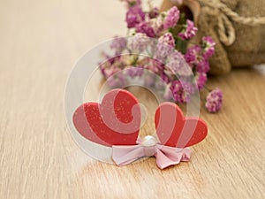 Valentines day background with red hearts on wood floor and blurred pink roses in background. Love concept