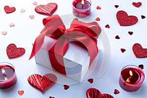 Valentines day background: red love hearts, romantic gift box, candle on white table. February romance present card