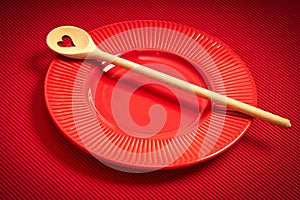 Valentines Day background with red plate and wooden spoon with heart on red background