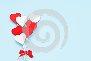 Valentines Day background. Red and white wooden hearts on a light blue backdrop. Flat lay, copy space