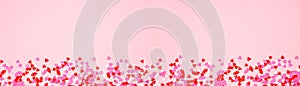 Valentines Day banner with border of candy heart sprinkles over a pink background with copy space