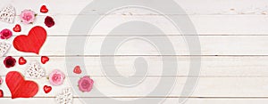 Valentines Day banner with corner border of hearts, flowers and decor against a white wood background with copy space