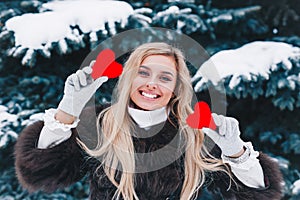 Valentines day. Beautifull smiling woman holding red hearts in the hands in the forest