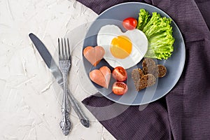 Valentines day breakfast with heart shaped fried eggs served on grey plate