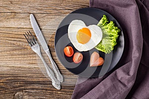 Valentines day breakfast with heart shaped fried eggs served on grey plate