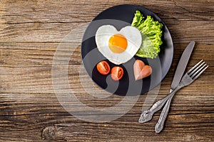 Valentines day breakfast with heart shaped fried eggs served on grey plate