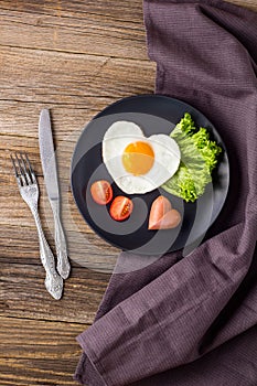 Valentines day breakfast with heart shaped fried eggs served on grey plate